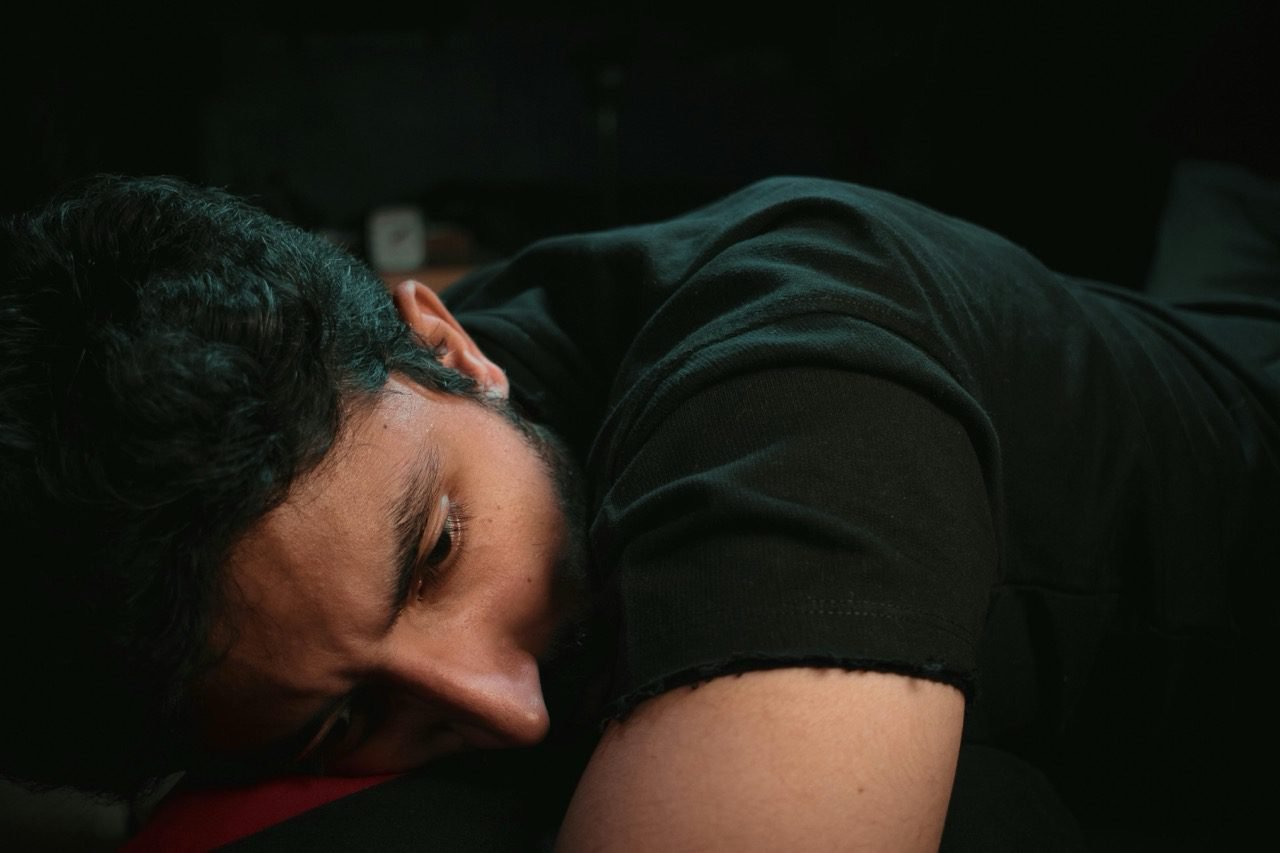 Pessoa sentada em ambiente escuro, simbolizando sofrimento emocional